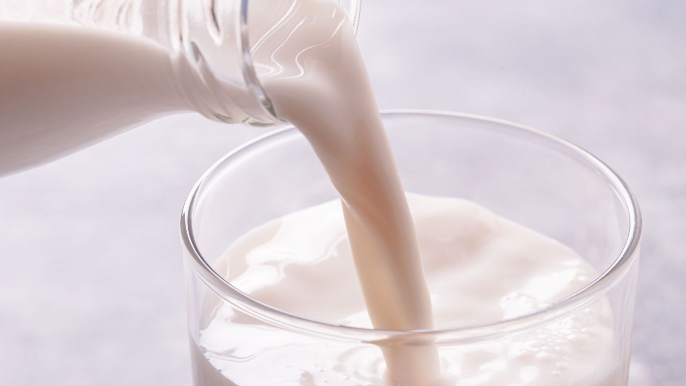 Milch wird aus einer Glasflasche eingeschenkt.